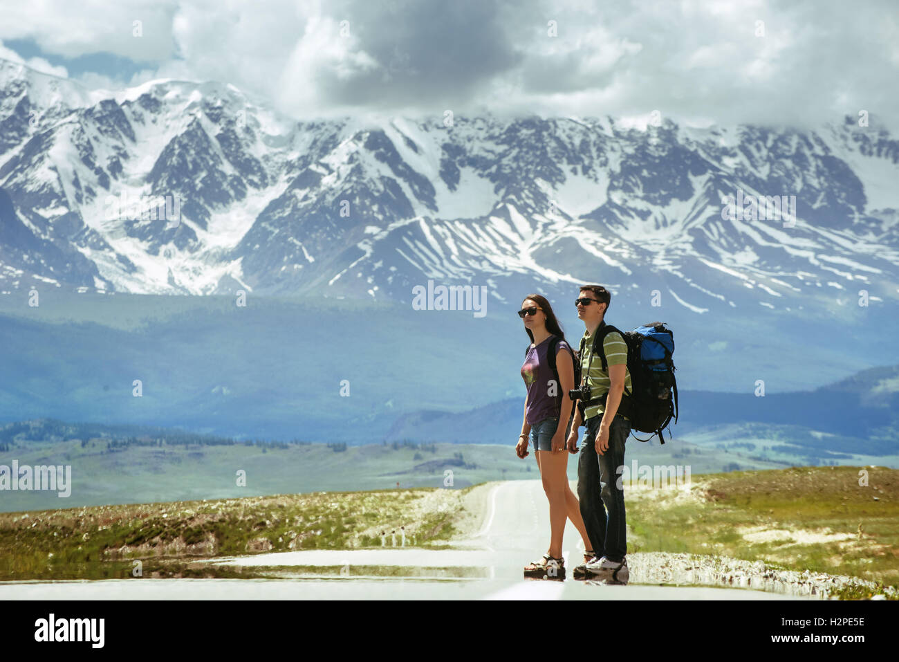 Coppia di viaggiatori rimane sulla strada delle bellissime montagne Foto Stock
