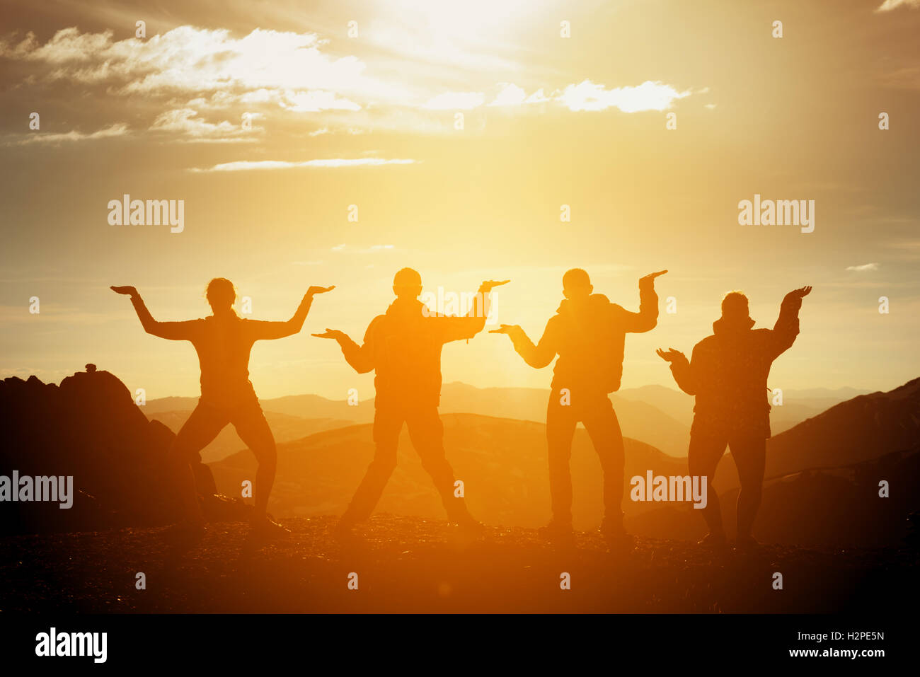 Gruppo di happy amici divertendosi su sfondo al tramonto Foto Stock