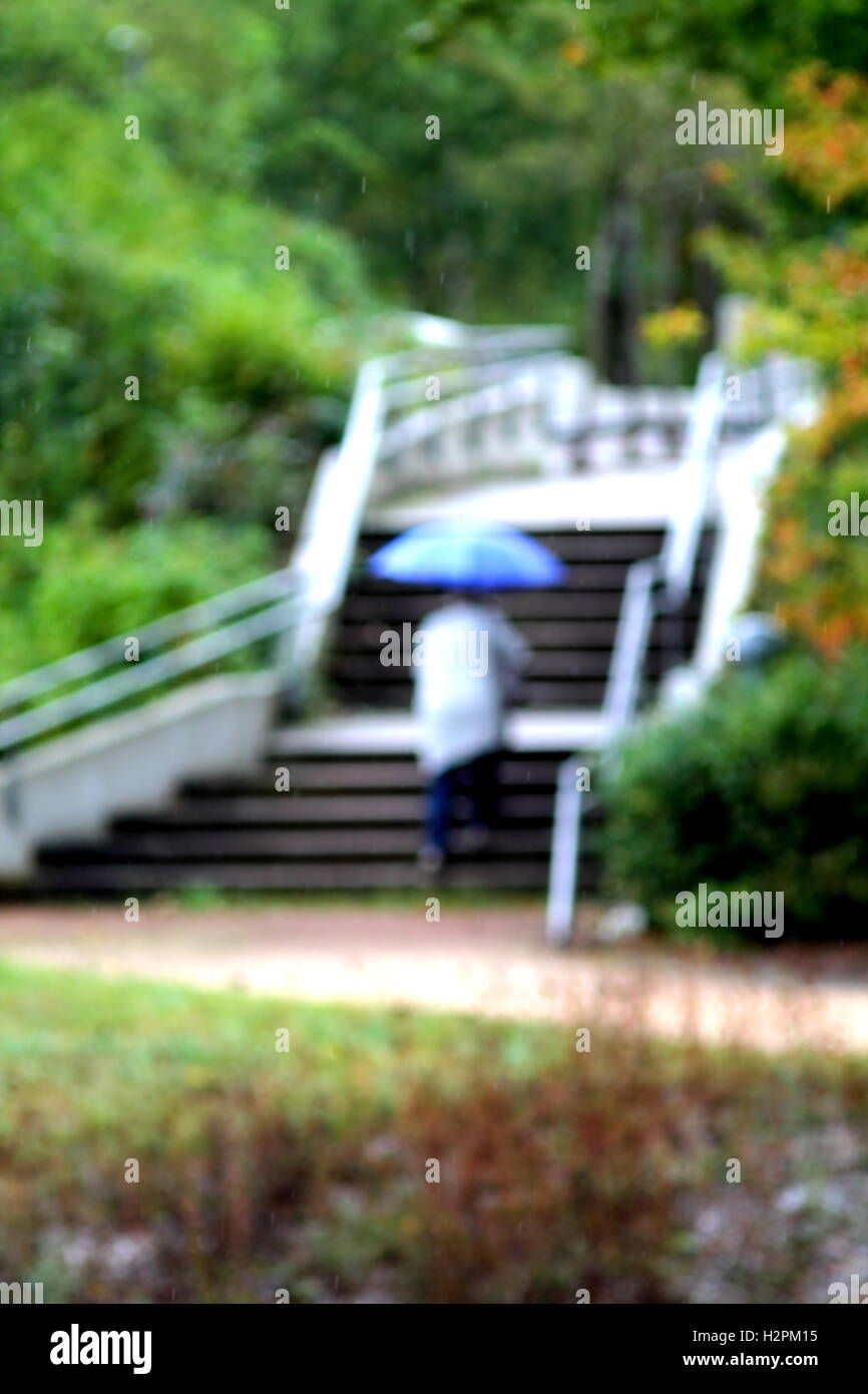 Abstract chiave di alta immagine sfocata di donna con ombrello blu a salire le scale. Foto Stock
