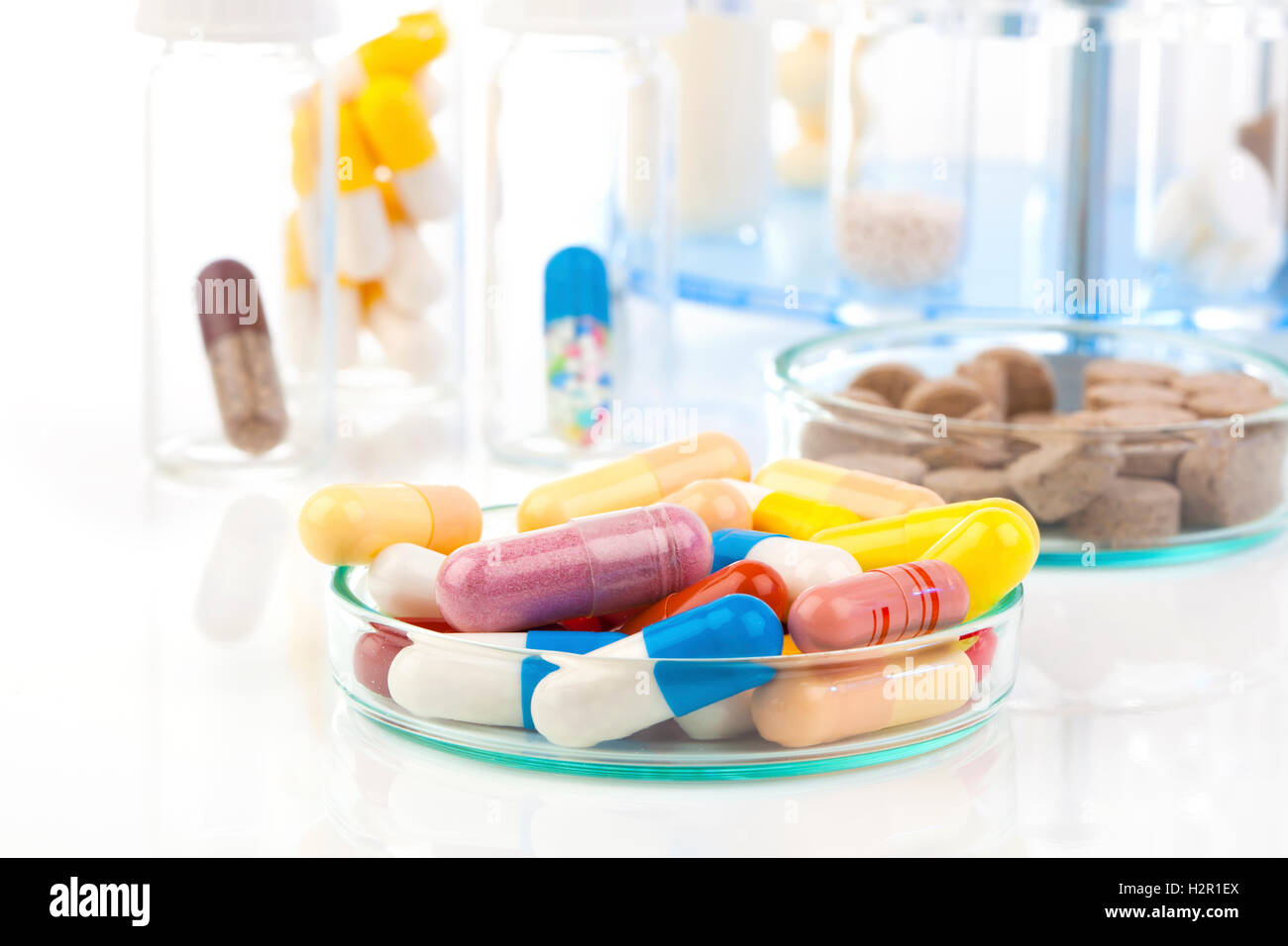 Colorate le capsule di medici in capsule di Petri. Concetto di laboratorio. Foto Stock