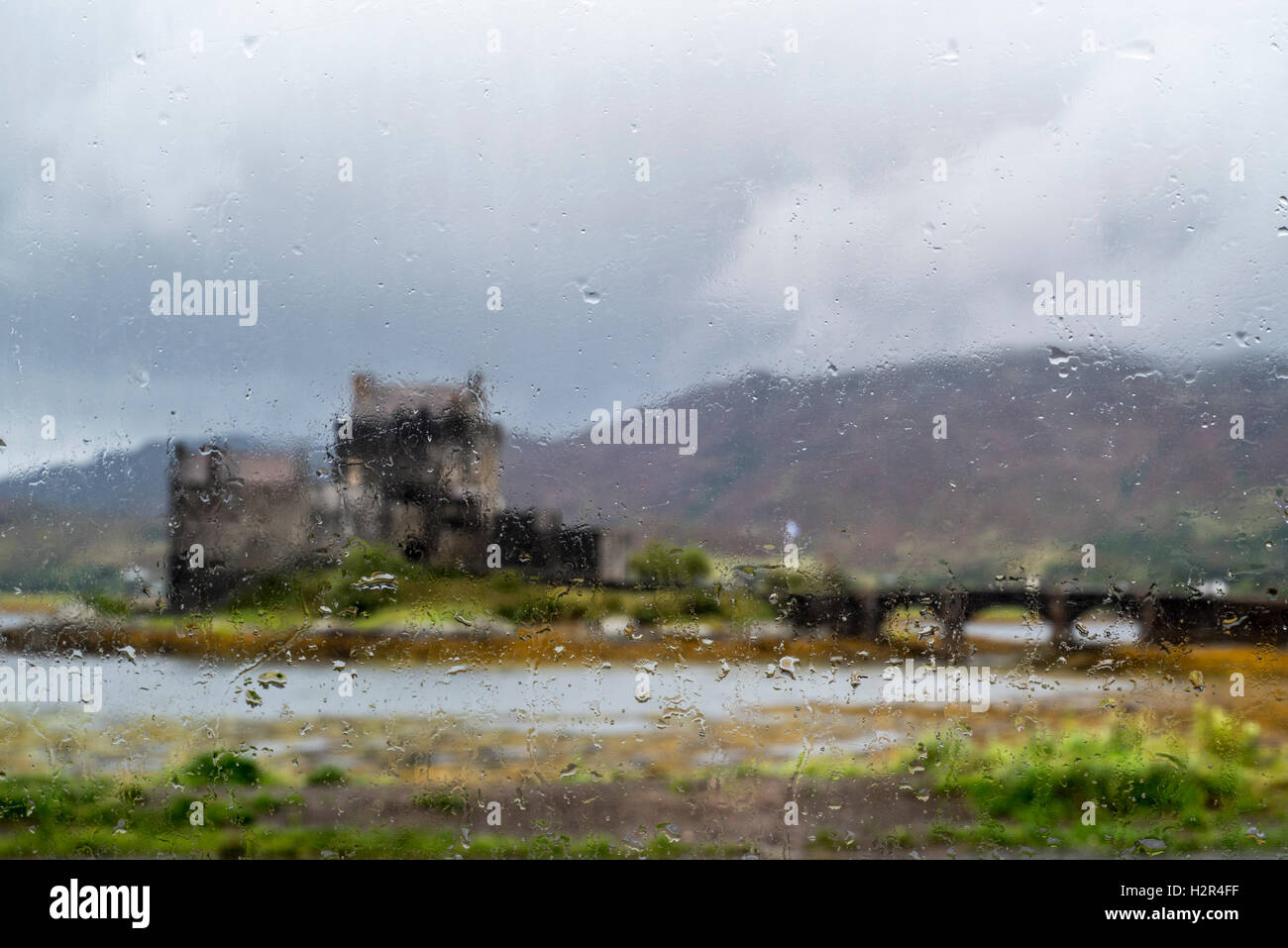 Eilean Donan Castle in Loch Duich visto attraverso la finestra con le gocce di pioggia a causa di forte pioggia, Ross and Cromarty, Highlands della Scozia Foto Stock