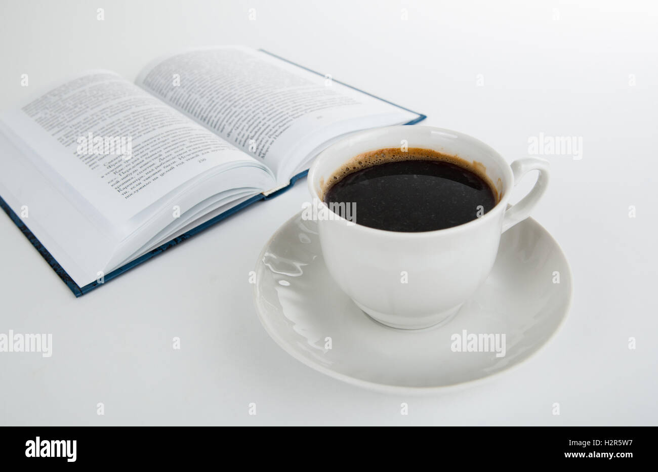 Tazza di caffè con il libro aperto su bianco Foto Stock