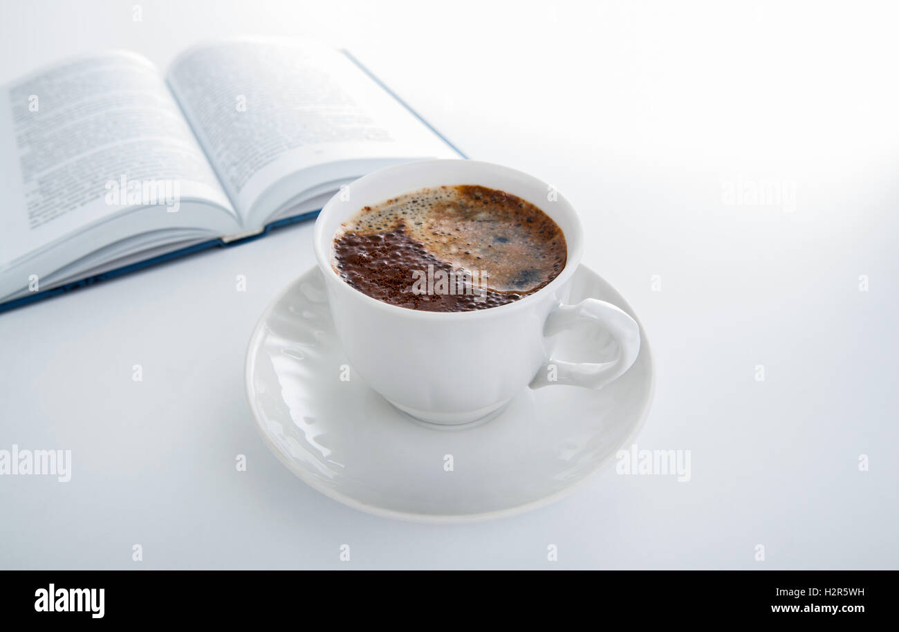 Tazza di caffè con il libro aperto su bianco Foto Stock