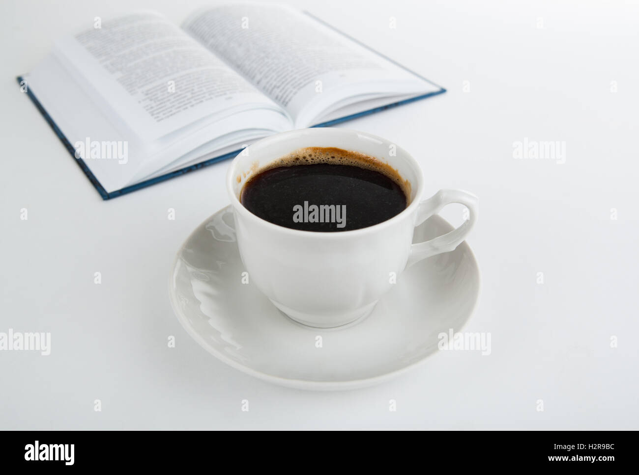 Tazza di caffè con il libro aperto su bianco Foto Stock