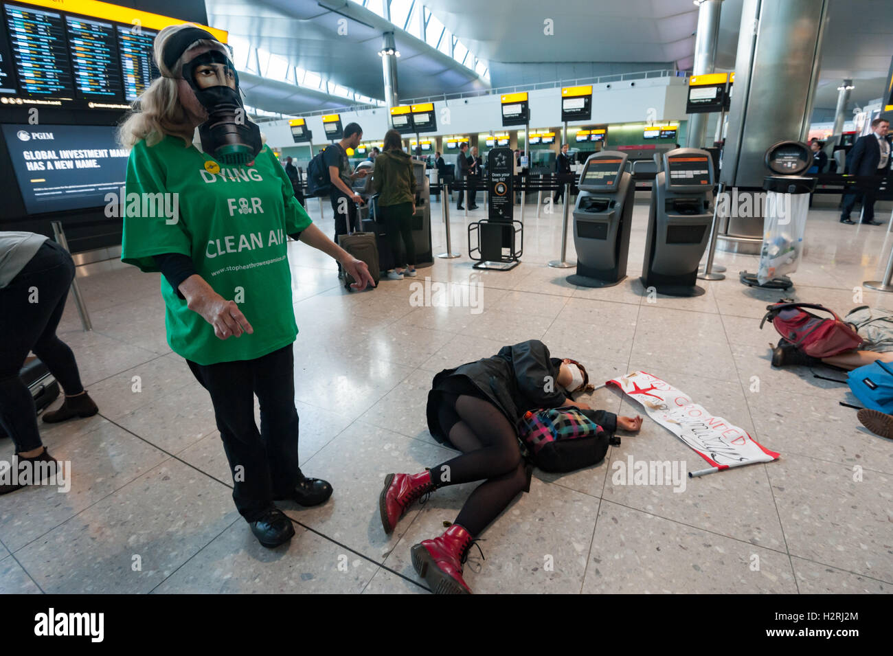 Aeroporto di Heathrow di Londra, Regno Unito. 1 ottobre 2016. Una donna che indossa una maschera a gas e una t-shirt con il messaggio 'Dying per aria pulita", evidenziando l'aria poolution causato da aviation presso il flash mob protesta all'interno del Terminal 2 di Heathrow contro l'impatto ambientale e sociale di aviazione. Heathrow è già un importante contributo all'inquinamento atmosferico a Londra sia per i voli e anche per il traffico dell'aeroporto genera. #StayGrounded protesta fu organizzata da rivendicare il potere, che ha anche messo in scena una 'red' linea di protesta da parte di ciclisti in aeroporto allo stesso tempo. Peter Marshall / Alamy Live News Foto Stock