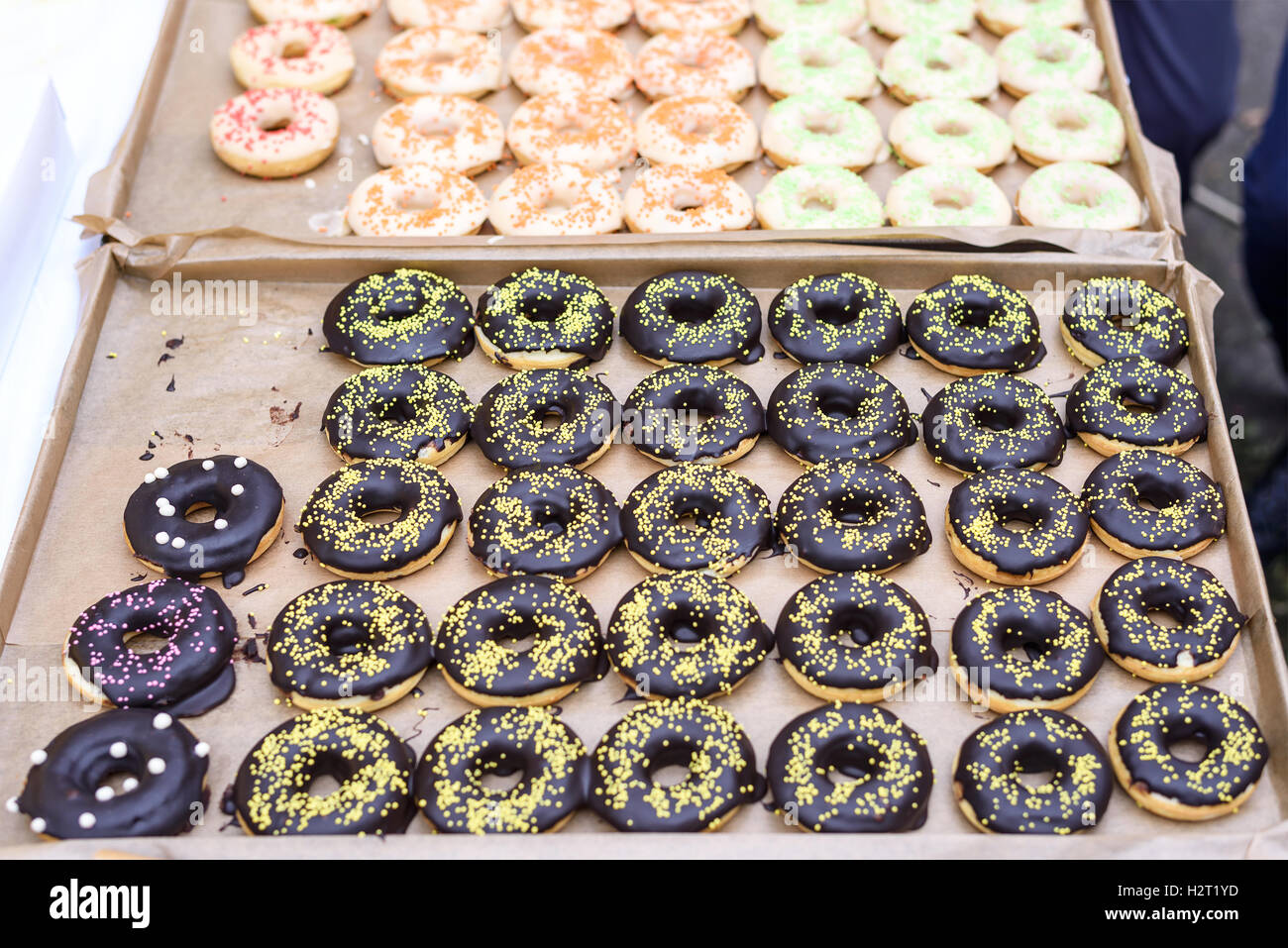 Ciambelle al cioccolato, giallo, rosso, arancione, rosa e zucchero verde sulla parte superiore, fondale focus Foto Stock