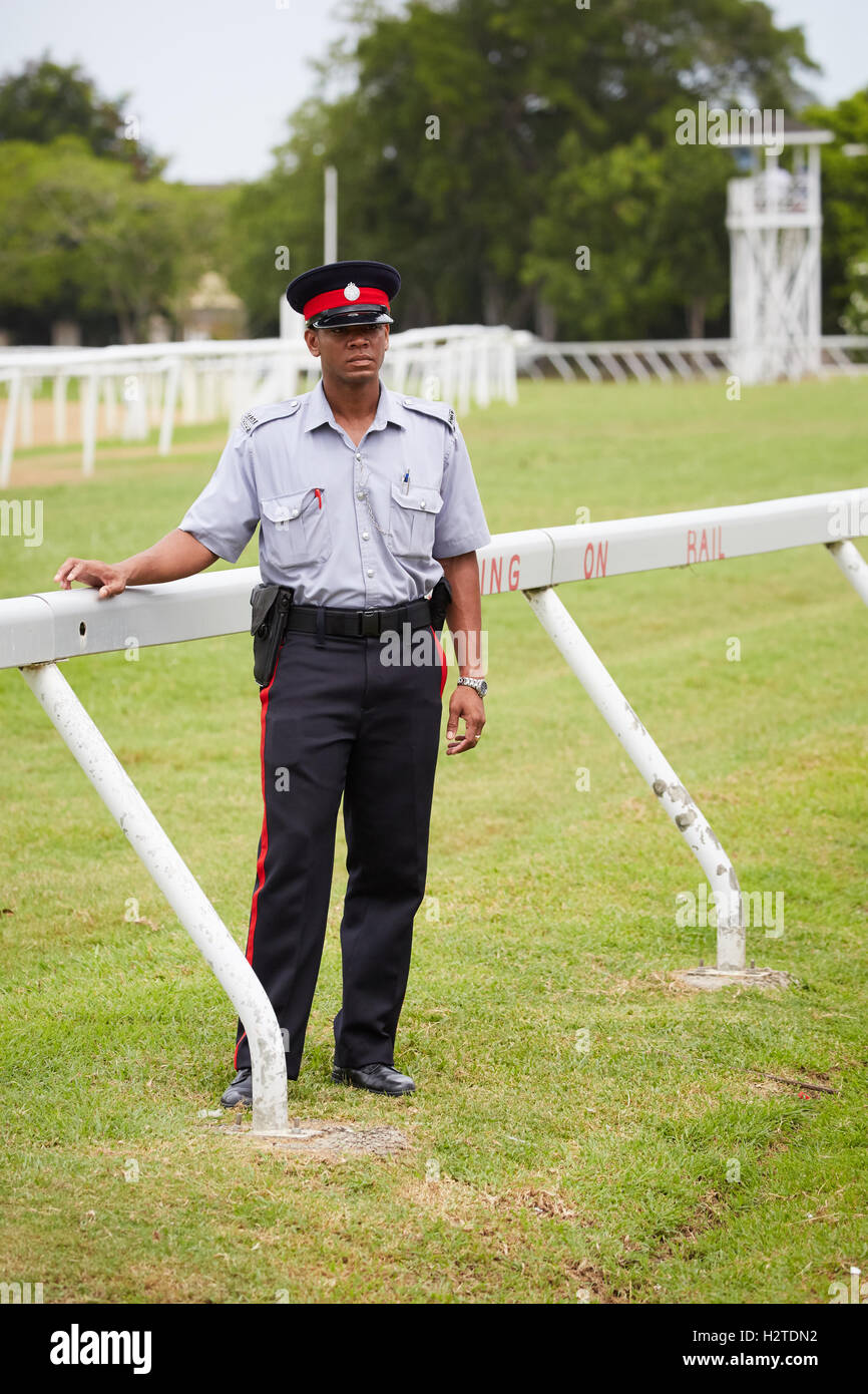 Barbados Bridgetown poliziotto ippodromo uniforme corso maschio nero uomo hat gun maniche corte funzionario di polizia constable PC bo Foto Stock