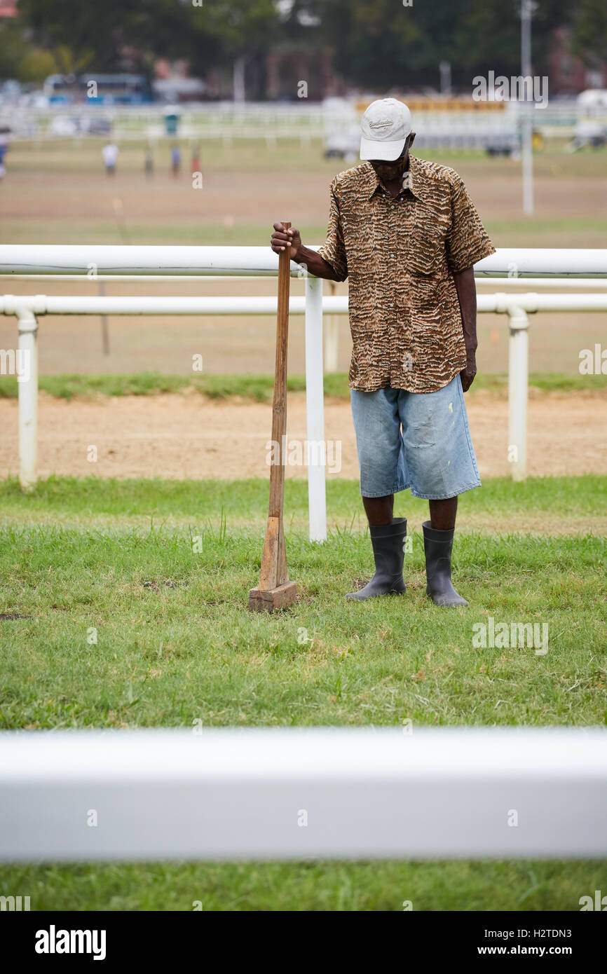 Barbados Bridgetown racecourse lavoratore via zolle d'erba corso maschio nero lavorando thumper colpi alla riparazione dei danni di danneggiare il da Foto Stock