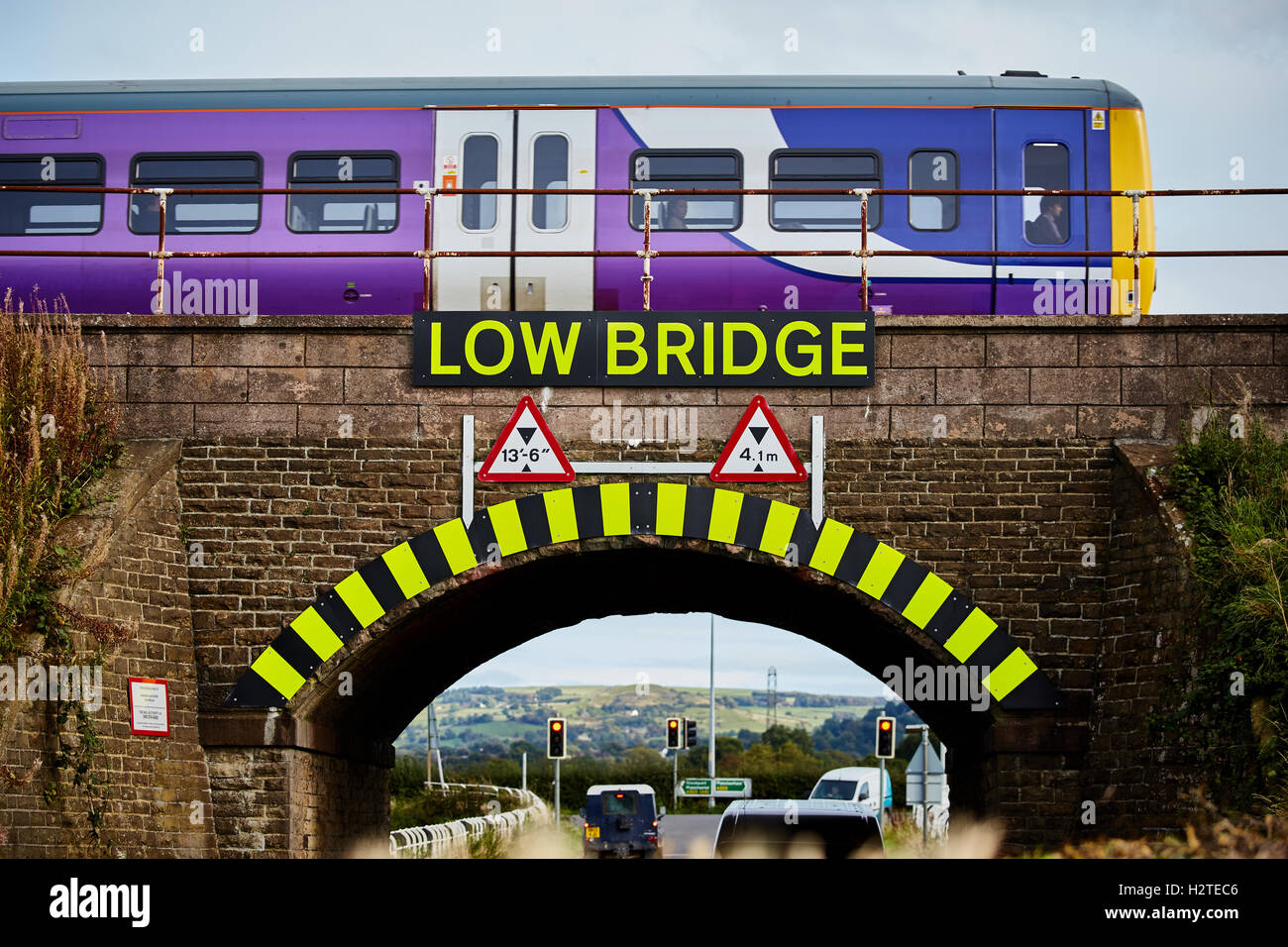 Bassa ponte ferroviario treno di avvertimento di servizio locale Adlington Manchester a Macclesfield la linea di trasporto Mezzi di trasporto del trasportatore Foto Stock