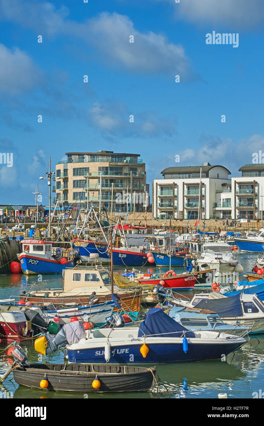West Bay nel Dorset è un piccolo porto di lavoro visto qui con un mix di lavoro barche da pesca. Il piccolo porto è stato centrale per la serie Broadchurch. Foto Stock