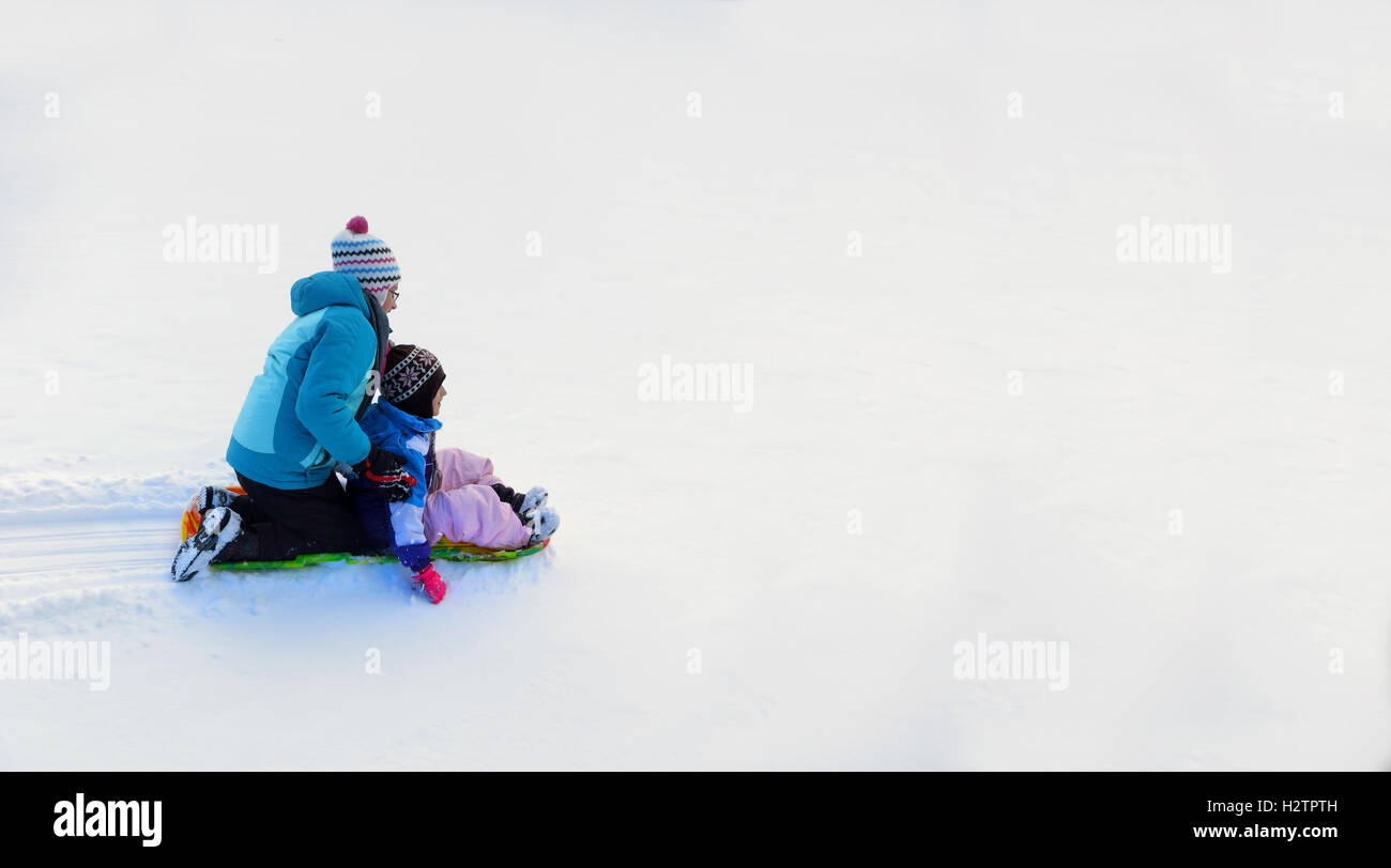 Bambini slittino giù collina innevate su sled veloce Foto Stock