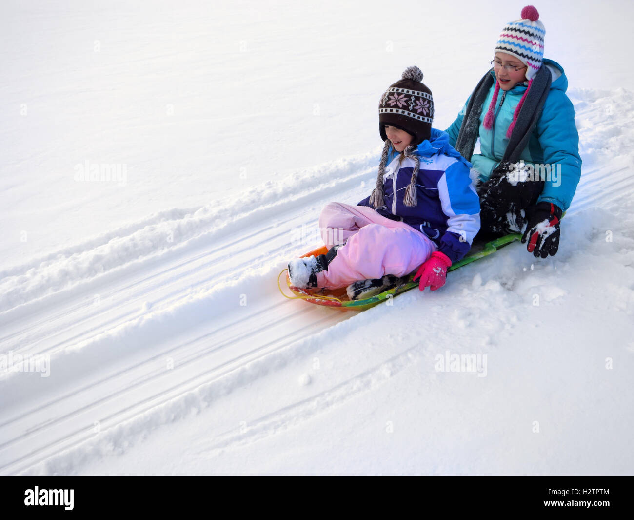 Bambini slittino giù collina innevate su sled veloce Foto Stock