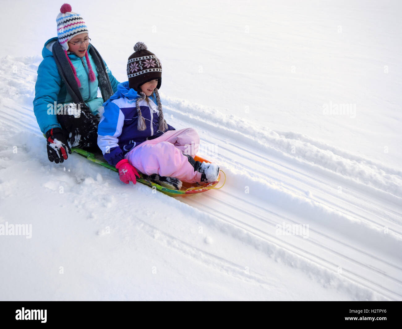 Bambini slittino giù collina innevate su sled veloce Foto Stock