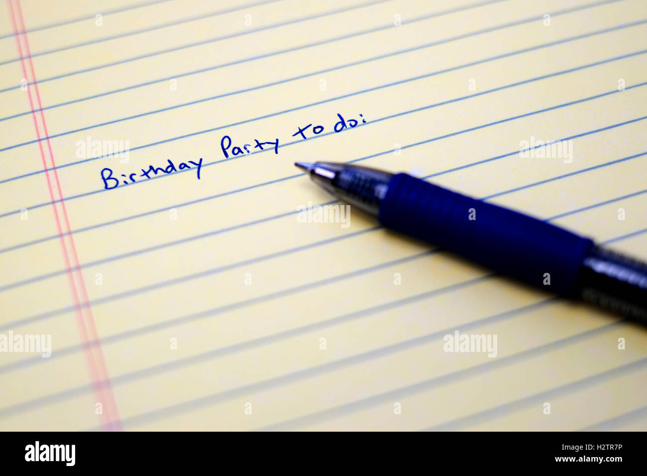 Primo piano della festa di compleanno Lista da fare su un foglio di carta con una penna blu scrittura scritta Foto Stock