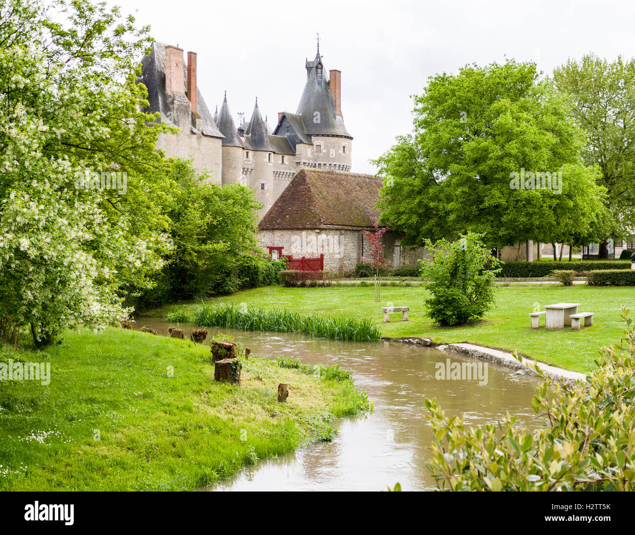 Flusso e parco presso Chateau de Fougeres-sur-Bievre. Un flusso ad alta flood brulica passato un grassy area picnic dietro la casa Foto Stock