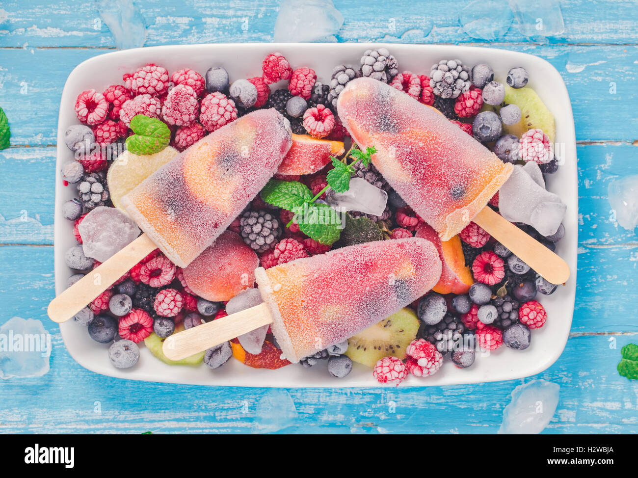 Pop di ghiaccio sulla piastra con frutti di bosco surgelati sopra Foto Stock