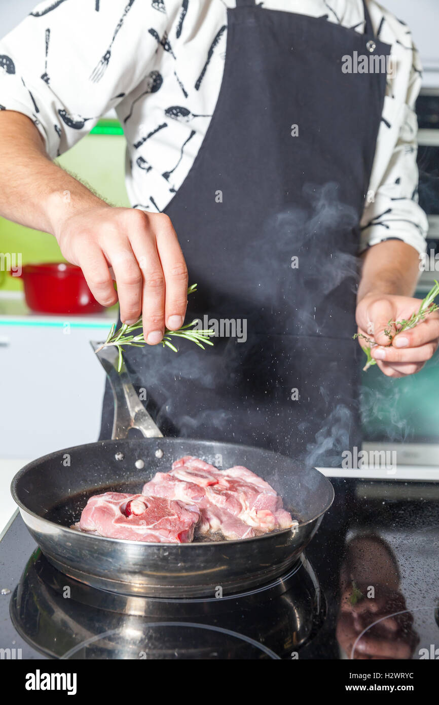 L'uomo l'aggiunta di rosmarino alla carne Foto Stock