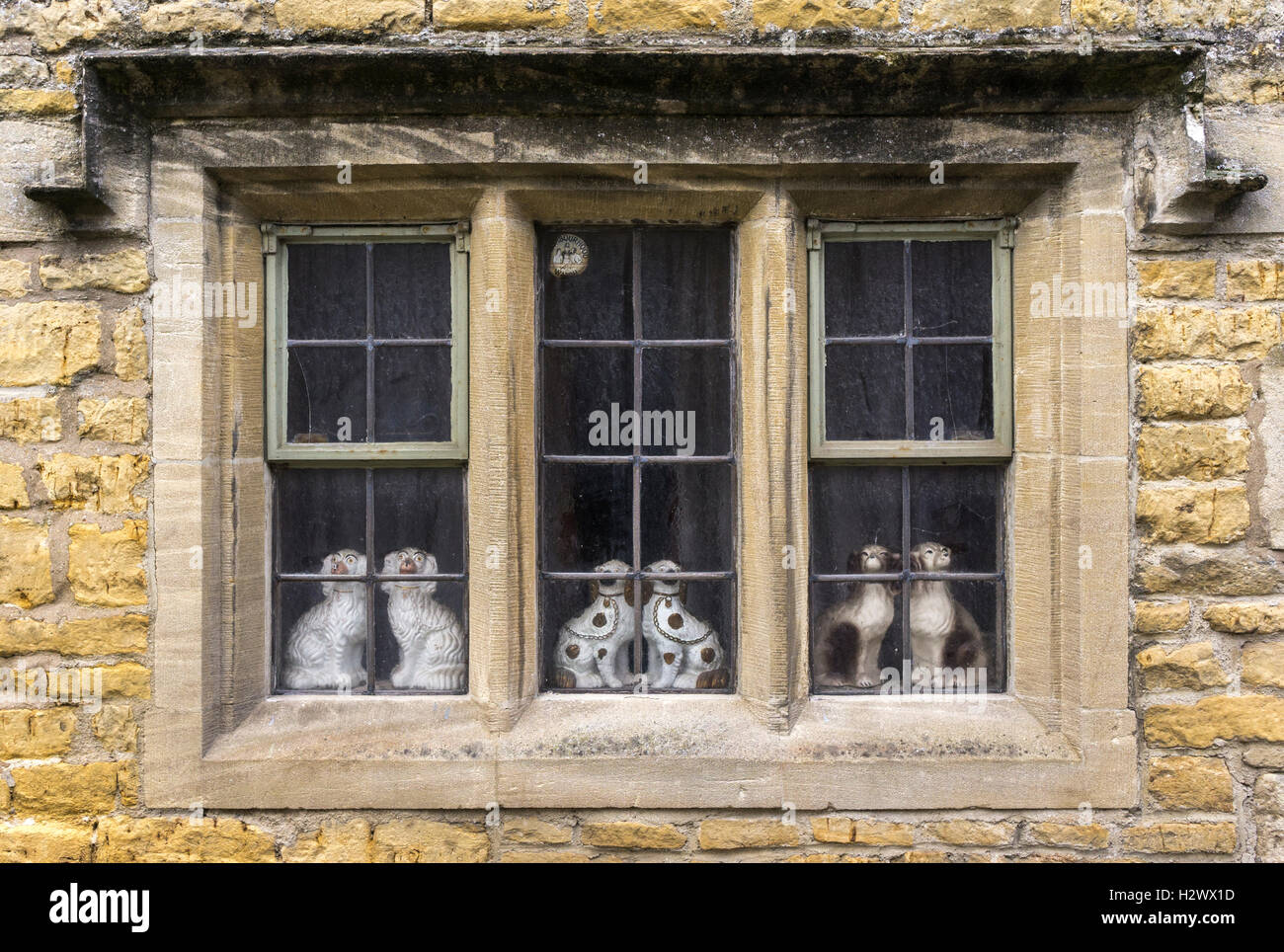Stafforshire cani in ceramica in un diciassettesimo cen. finestra, Bourton sull'acqua, Cotswolds, Glousteshire, Inghilterra. Foto Stock