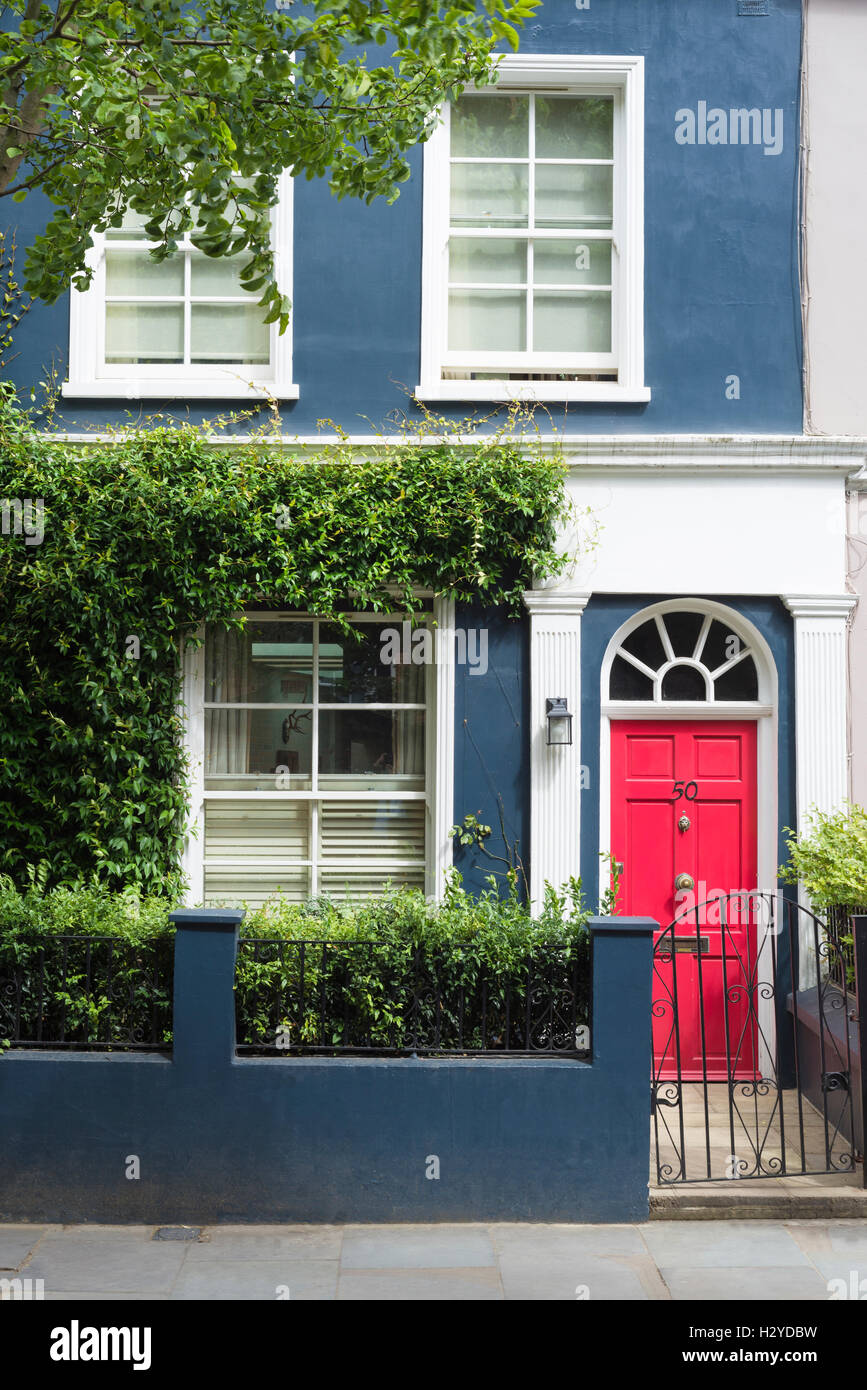 Coloratissima casa blu facciata rossa e sportello anteriore in architettura georgiana a Portobello Road a Notting Hill in estate, London, Regno Unito Foto Stock