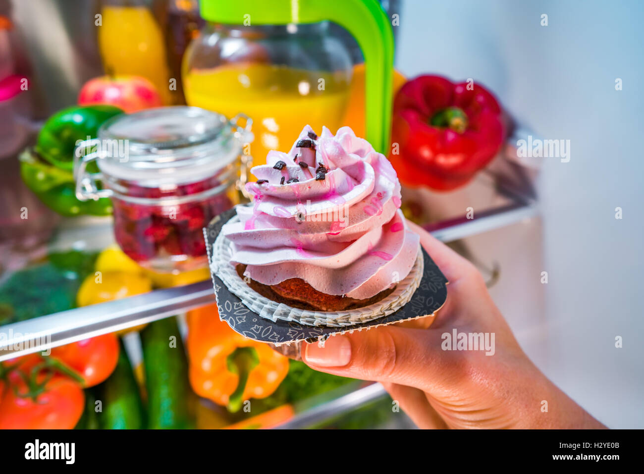 La donna prende la torta dolce dal frigorifero aperto Foto Stock