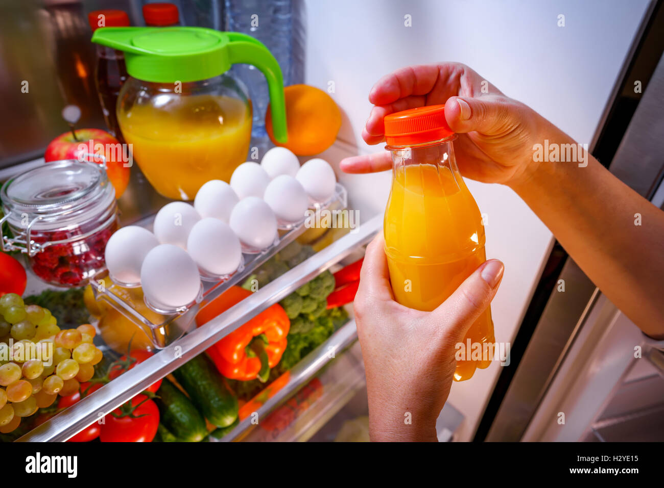 La donna prende il succo di arancia dal frigorifero aperto Foto Stock