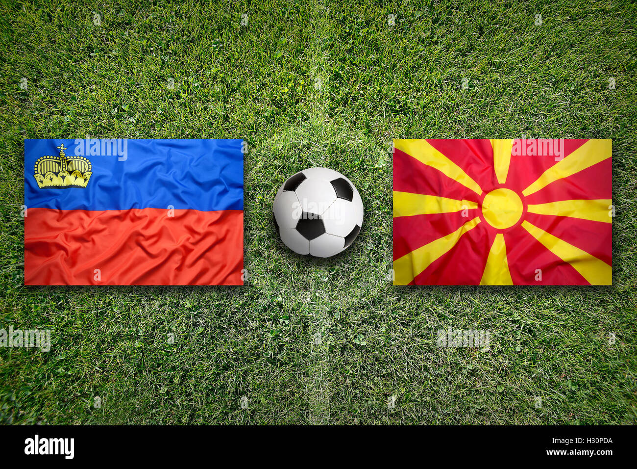 Il Liechtenstein vs. Macedonia bandiere sul verde del campo di calcio Foto Stock