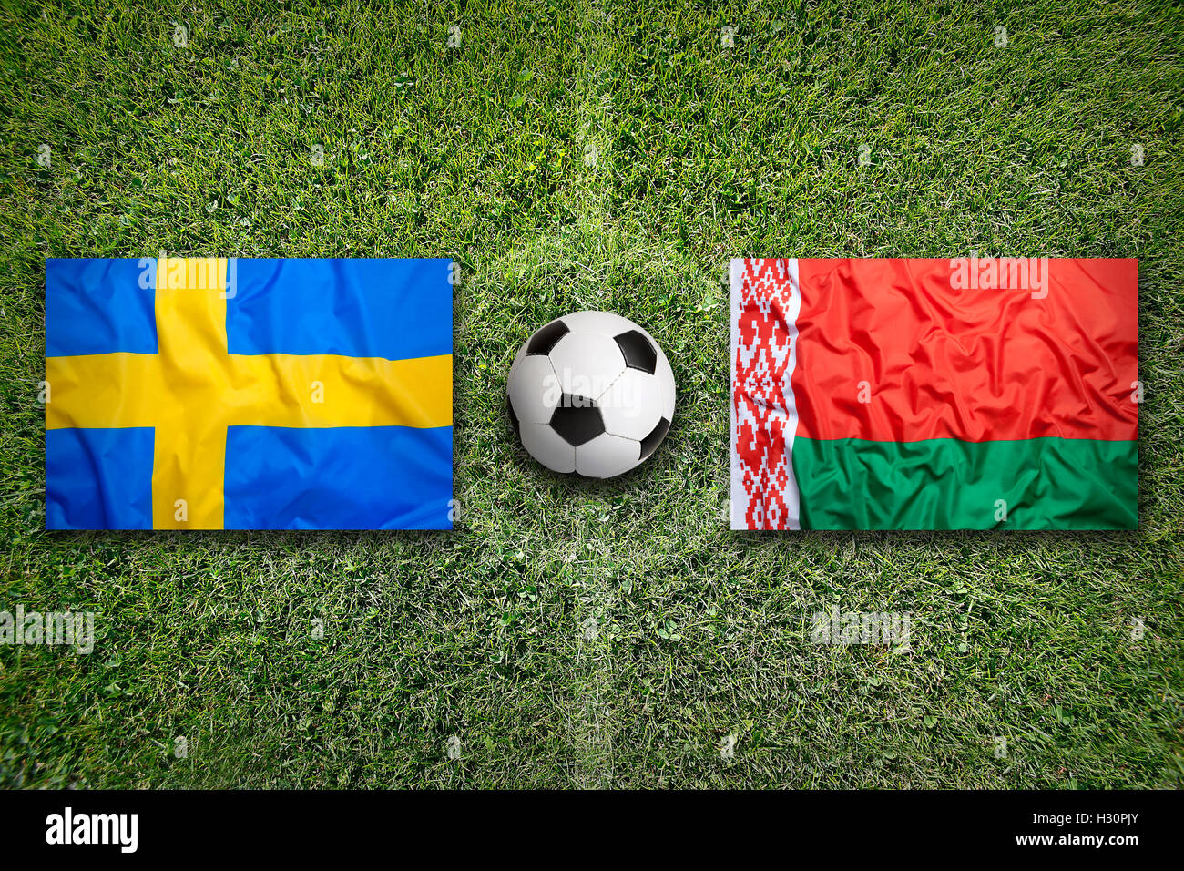 La Svezia vs. Bielorussia bandiere sul verde del campo di calcio Foto Stock