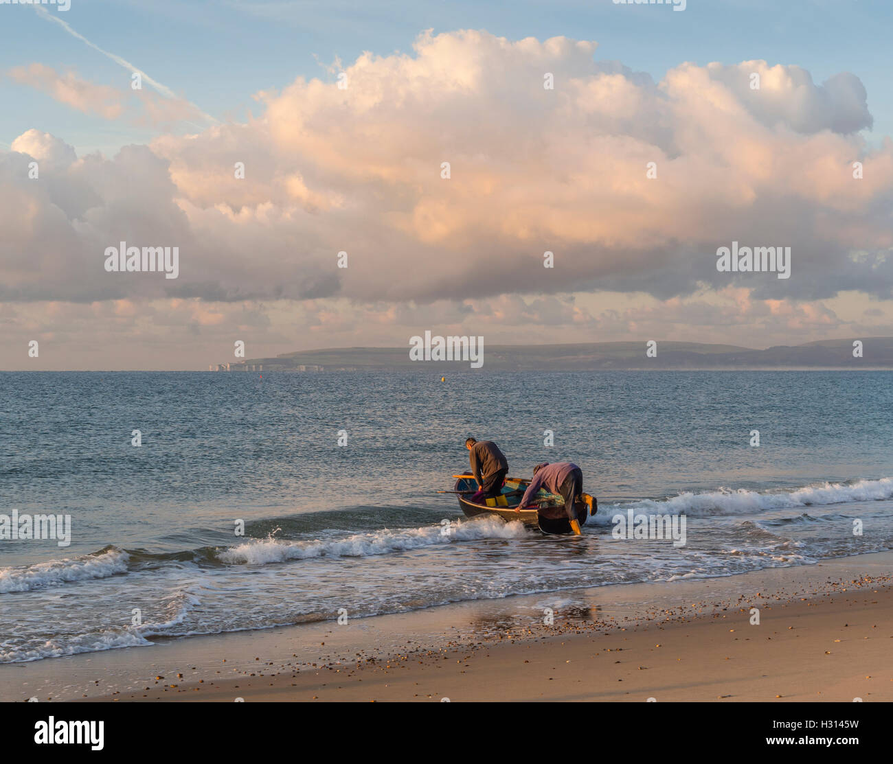 Due pescatori di uscire in barca a remi, off Bournemouth Beach, a pescare nella baia di Poole, Dorset, Regno Unito Foto Stock