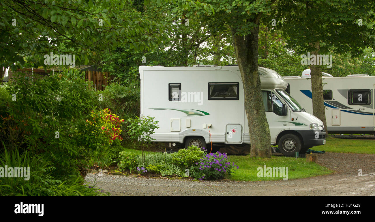 Camper moderno / casa mobile tra alberi di ombreggiatura e verdeggiante di prati e giardini colorati a Ravenglass caravan park, Cumbria Inghilterra England Foto Stock