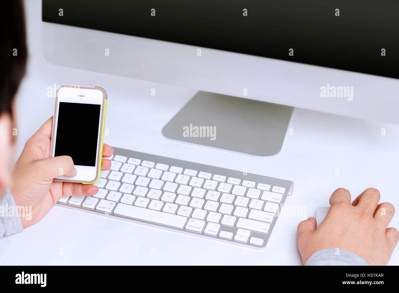 Gentleman utilizzando il telefono cellulare mentre si lavora sul desktop Foto Stock