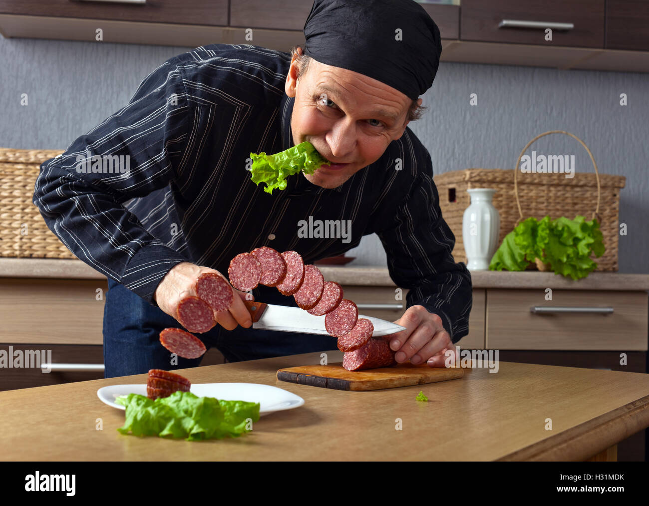 L'uomo il taglio delle fette di salame sul tavolo della cucina Foto stock -  Alamy