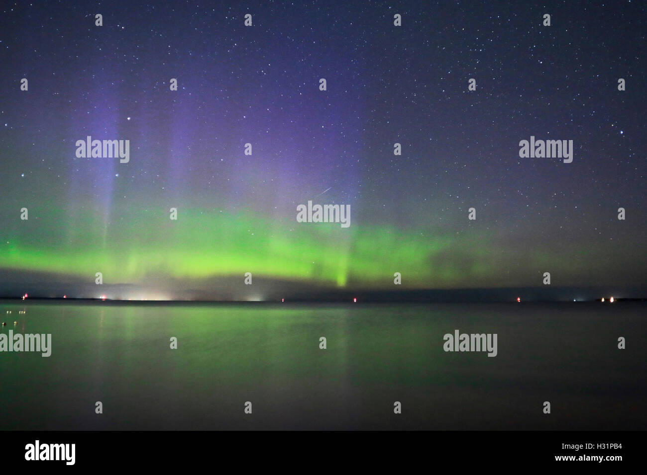 Aurora con verde e viola i colori danzanti nel lago, Perseid Meteor doccia sentiero di luce a cadere dal cielo. Foto Stock