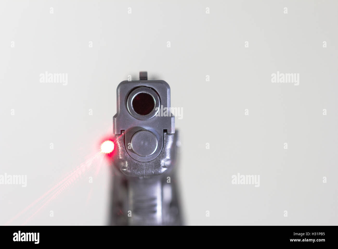 Primo piano della fine della canna della pistola con laser trail Foto Stock