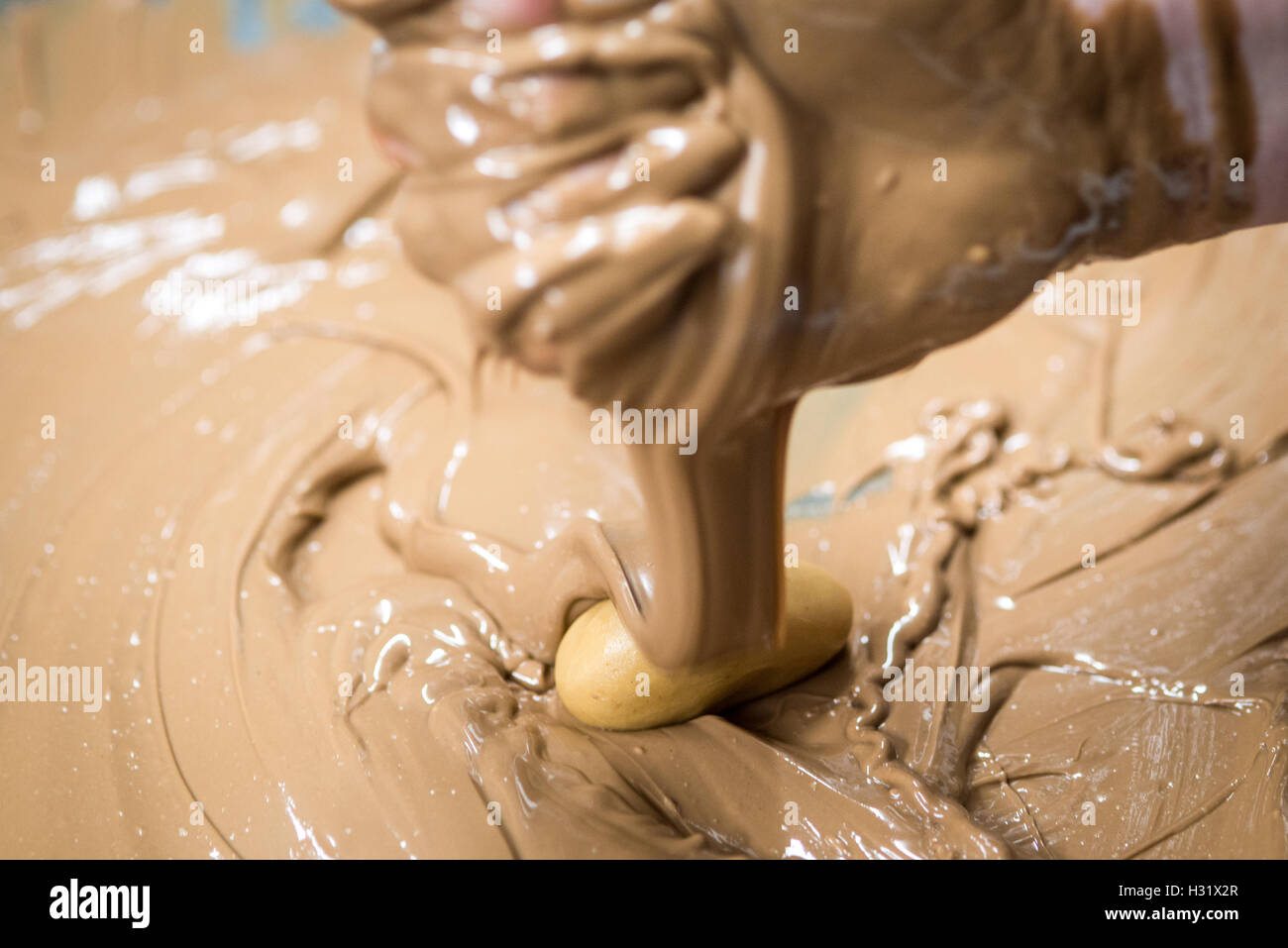 Una mano colata di cioccolato fuso su un burro di arachidi uovo di Pasqua Foto Stock