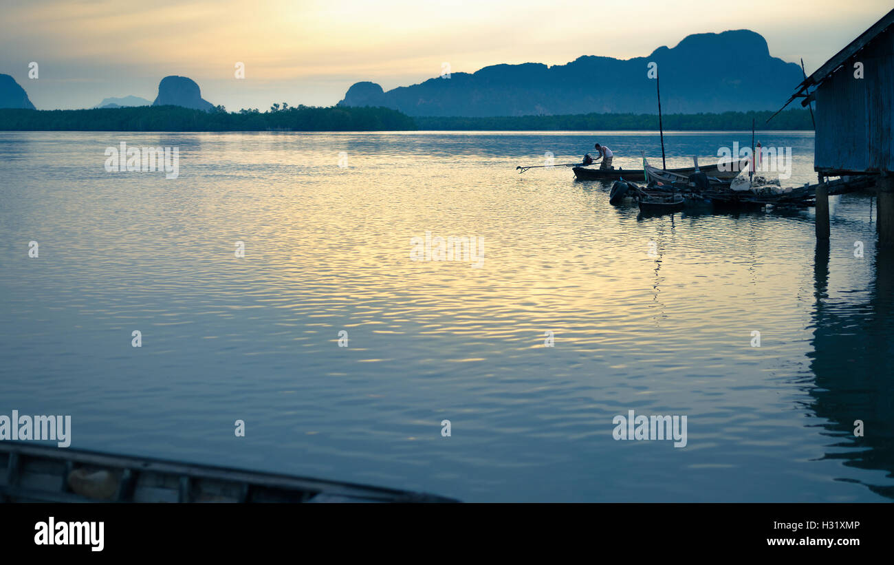 Phang-Nga, Thailandia - Agosto 9,2014: Thai pescatore in coda lunga barca da pesca a Samchong borgo peschereccio di sunrise in Phang-Ng Foto Stock