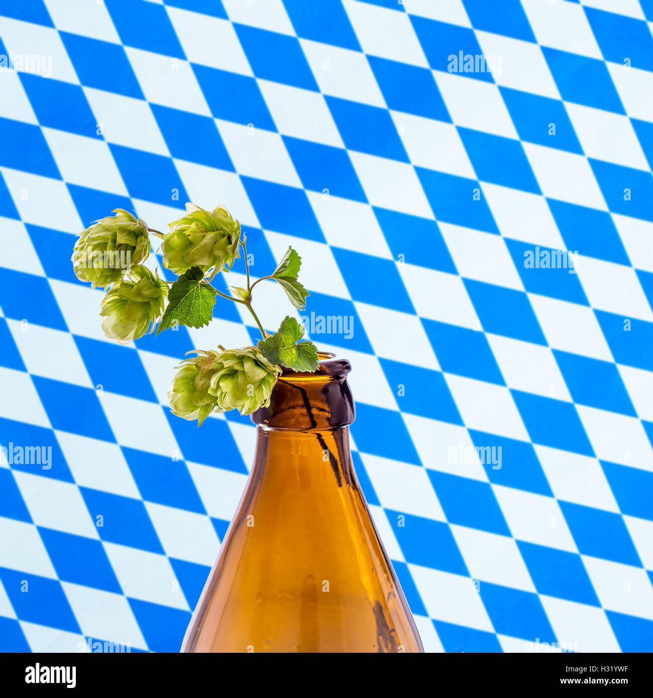 Bottiglia di birra con hop branch, su bianco blu bandiera bavarese Foto Stock