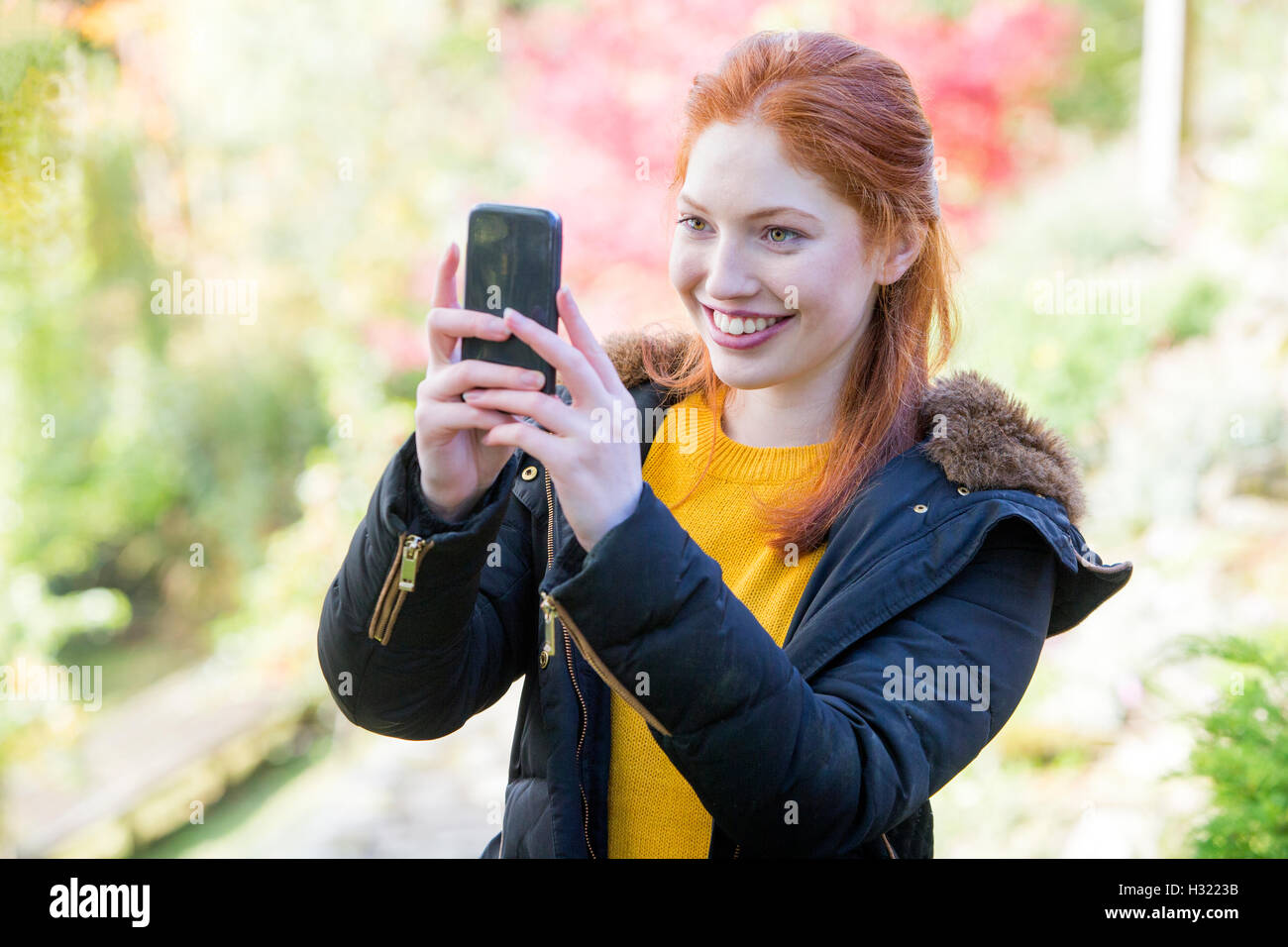 Giovane donna di scattare una foto della natura sul suo smartphone. Foto Stock