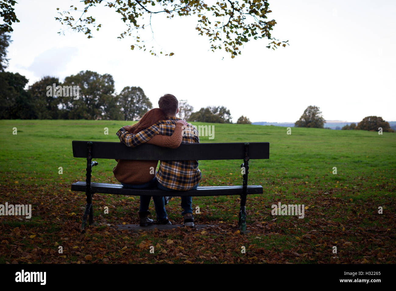 Coppia giovane cuddling su un banco in un parco. Foto Stock