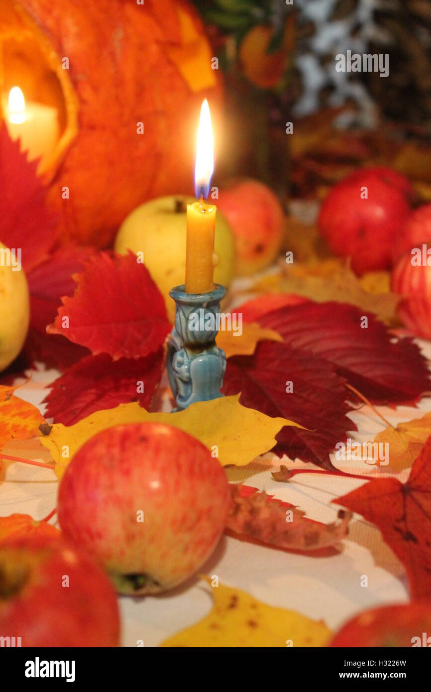 Poco brillante cera per candele accese soggiorno su foglie di autunno e mele gratitudine per il raccolto Foto Stock