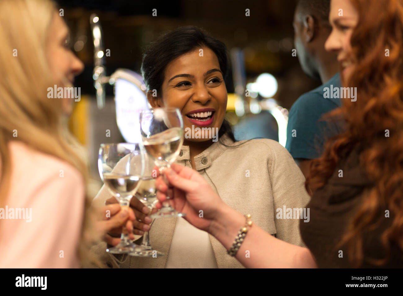 Tre donne tostare i loro bicchieri in un bar Foto Stock