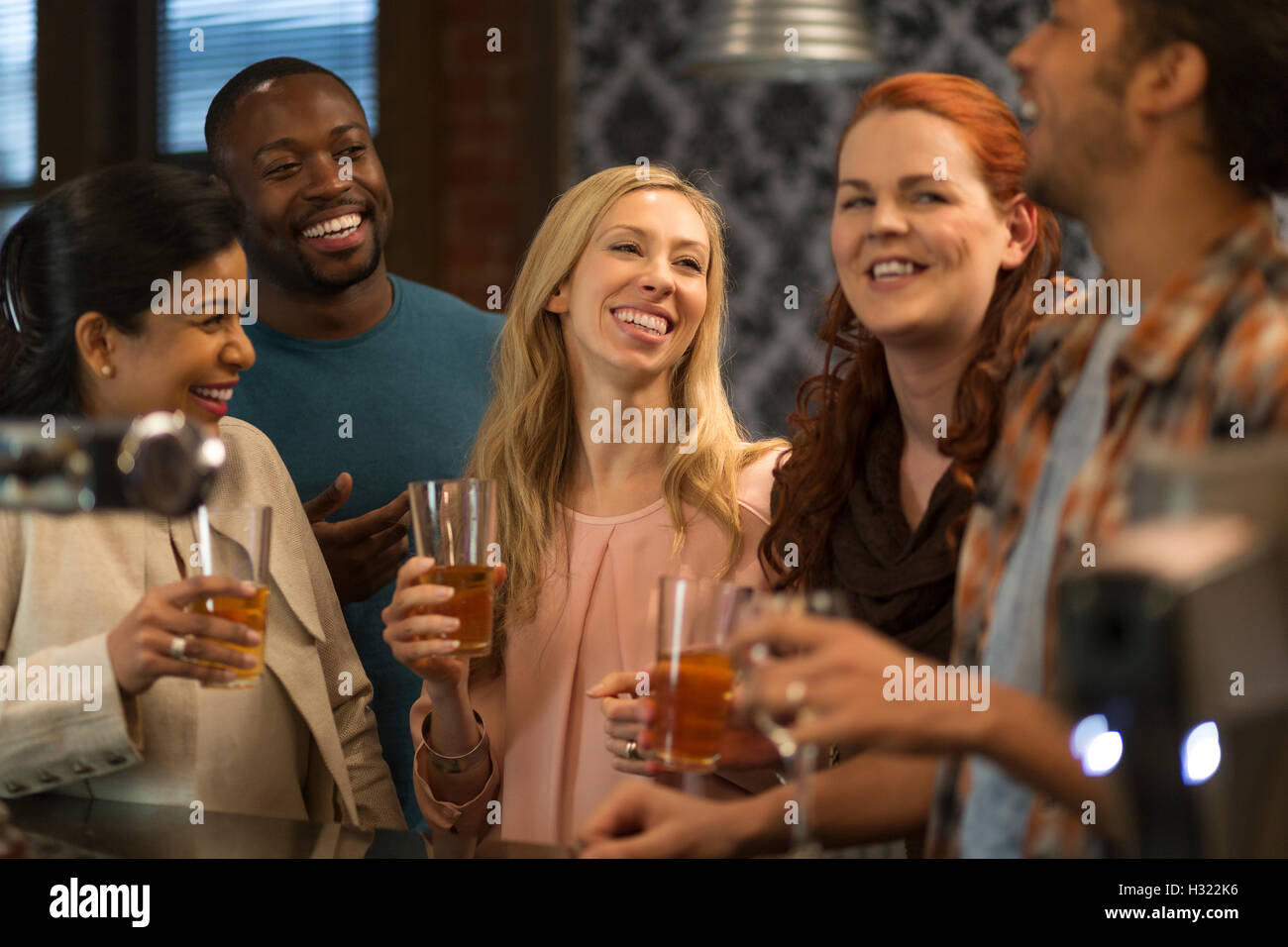 Gruppo di amici a bere birra al bar. Essi sono tutti a ridere e parlare a vicenda. Foto Stock