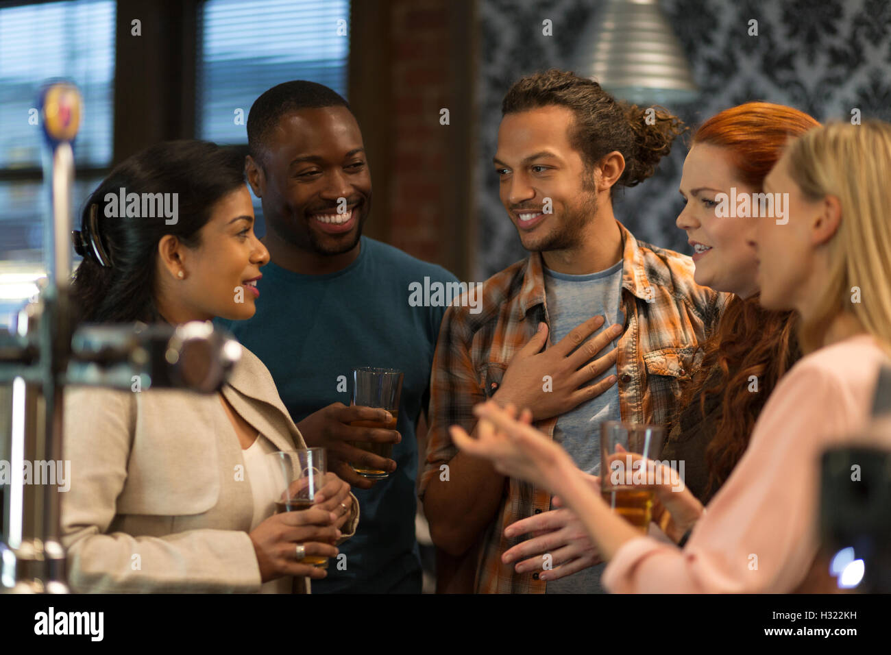 Gruppo di amici a bere birra al bar. Essi sono tutti di ridere e di parlarsi. Foto Stock