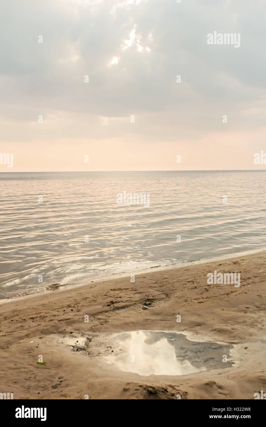 Pozza in sabbia sulla riva del mare in estate tramonto Foto Stock