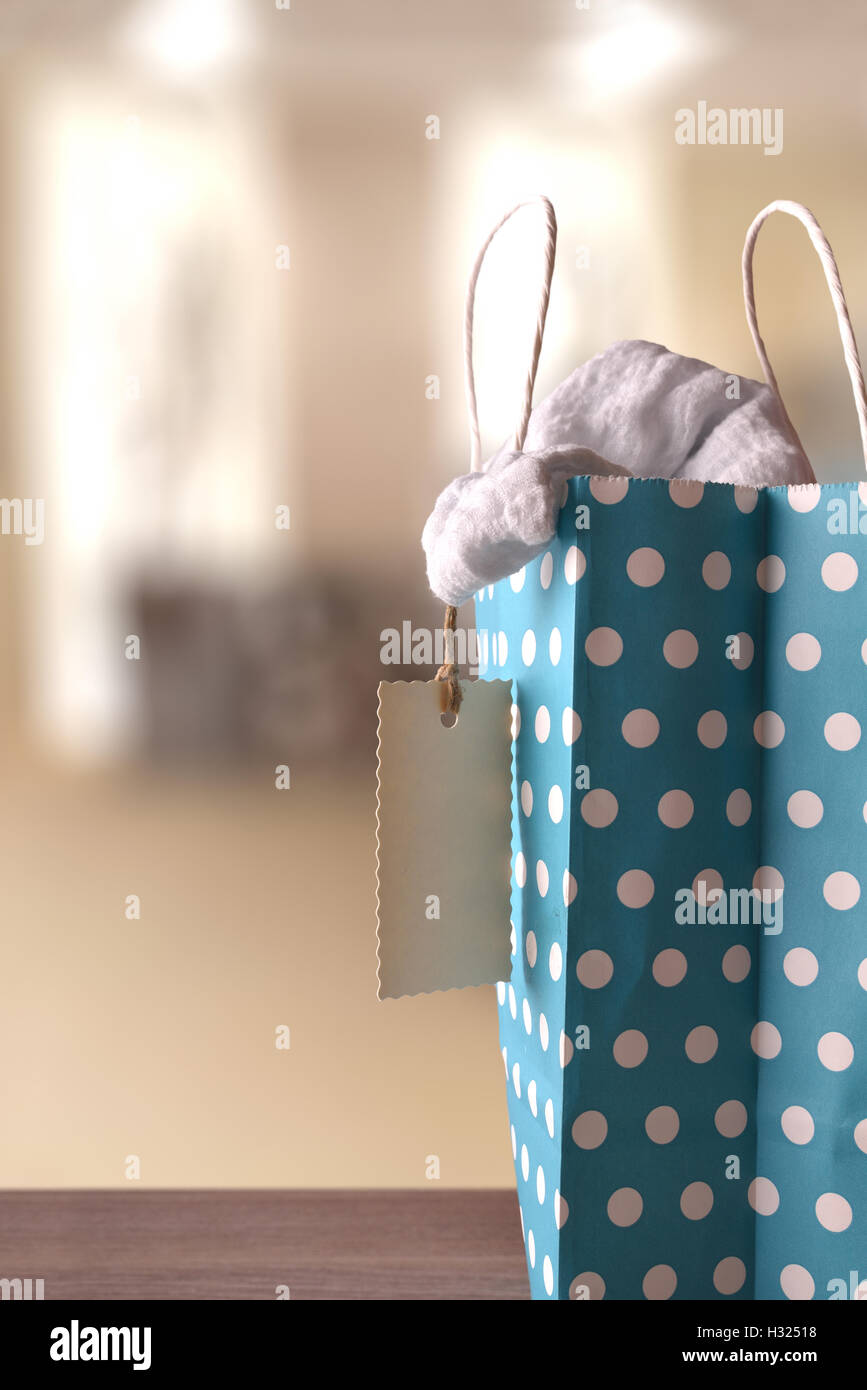 Borsa blu per comprare con cerchi bianchi sulla tavola di legno con nuovi vestiti all'interno di in un negozio.Tag dettaglio. Vista frontale. Composizione verticale Foto Stock