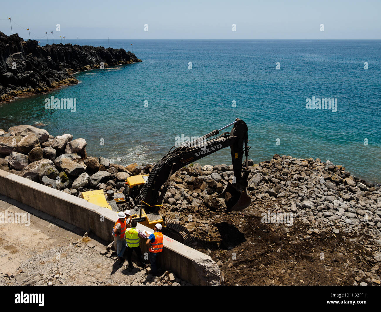 Un escavatore lavora sul litorale della stabilizzazione a Camara de Lobos sull'isola portoghese di Madeira Foto Stock