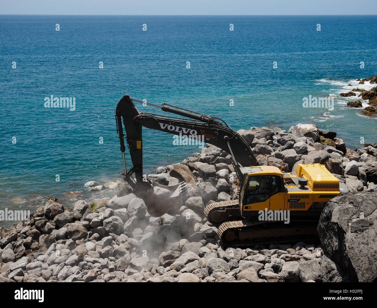 Un escavatore lavora sul litorale della stabilizzazione a Camara de Lobos sull'isola portoghese di Madeira Foto Stock