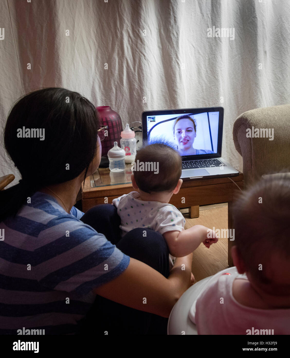 Twin neonati guardando la madre su Skype sul computer Foto Stock