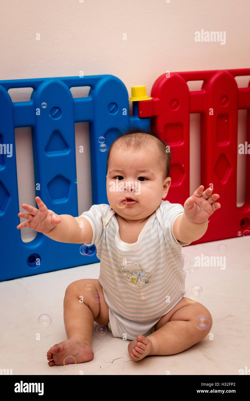 Baby cercando di catturare le bolle Foto Stock