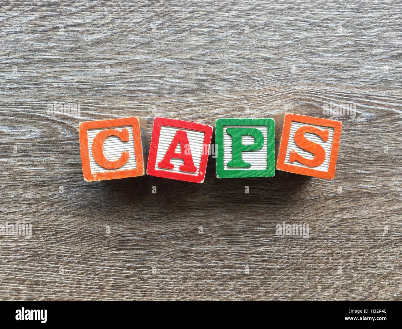 Alfabeto blocco di legno lettere che compongono la parola CAPS, è un modo per i giovani i bambini ad imparare le parole in inglese in un modo divertente Foto Stock