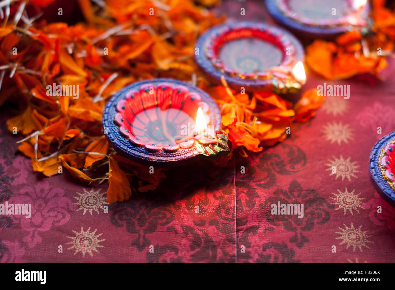 Diya lampade accese durante il Diwali celebrazione con fiori e dolci in background Foto Stock